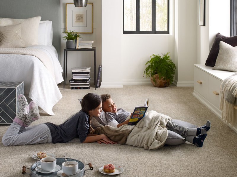 kids laying on floor of bedroom reading a book