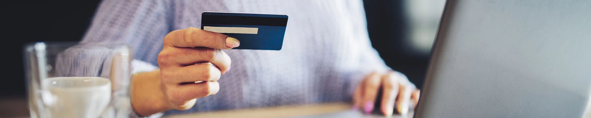 woman holding credit card while using computer